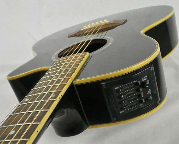 A black electroacoustic guitar. Close up of the neck and electronics.