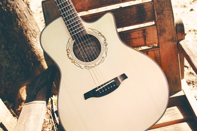 A light coloured acoustic guitar. This type of guitar is also known as a steel string guitar.