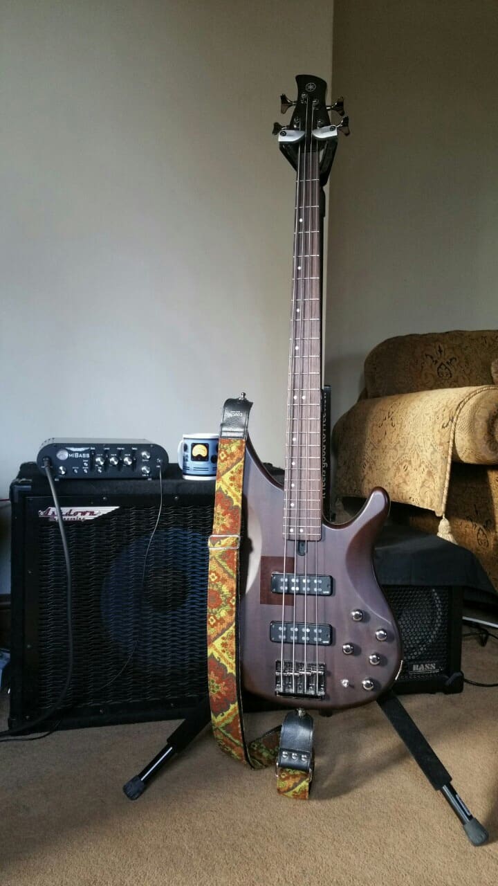 A bass guitar front of a bass amp on a stand